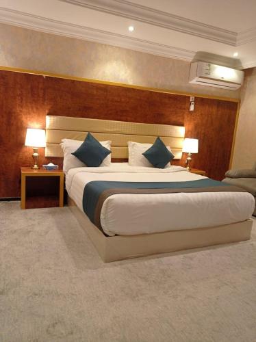 a hotel room with a large bed with blue pillows at ليالي العاذريه للشقق المخدومة in Al Namas