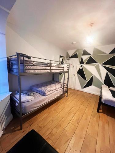 a room with two bunk beds in it with a wall with triangles at Old Trafford Guest House in Manchester