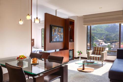 a living room with a glass table and chairs at NH Collection Bogota Hacienda Royal in Bogotá