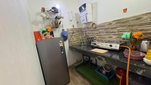 a small kitchen with a refrigerator and a counter at Varāya 1RK Studio in Vrindāvan