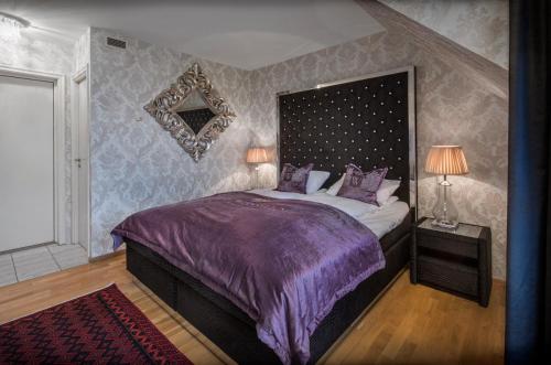 a bedroom with a bed with a purple bedspread at Hotel Wassilioff - Unike Hoteller in Stavern