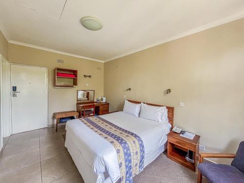 ein Hotelzimmer mit einem Bett und einem Stuhl in der Unterkunft Baines Bed & Breakfast in Harare