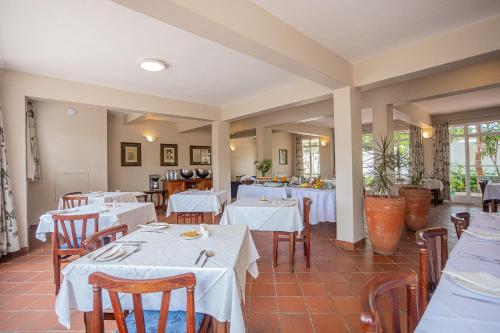 ein Esszimmer mit weißen Tischen und Stühlen in der Unterkunft Baines Bed & Breakfast in Harare