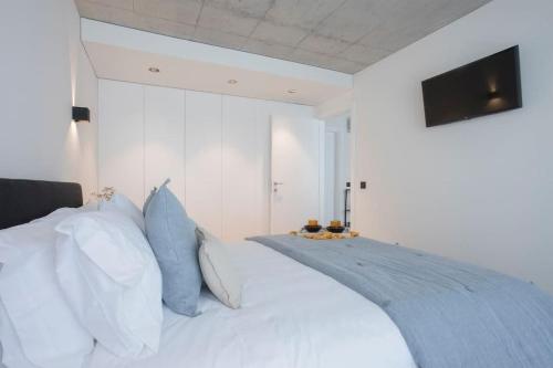 a bedroom with a white bed with blue pillows at Liiiving in Gaia - Beach Seaside Apartment in Vila Nova de Gaia