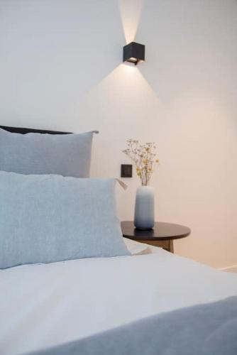 a bed with blue pillows and a vase on a table at Liiiving in Gaia - Beach Seaside Apartment in Vila Nova de Gaia