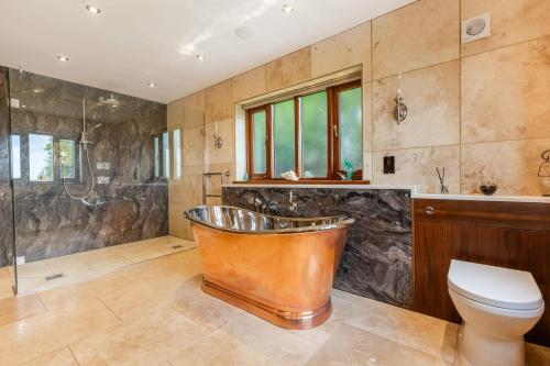 a bathroom with a copper tub and a toilet at Broadridge Manor in West Worlington