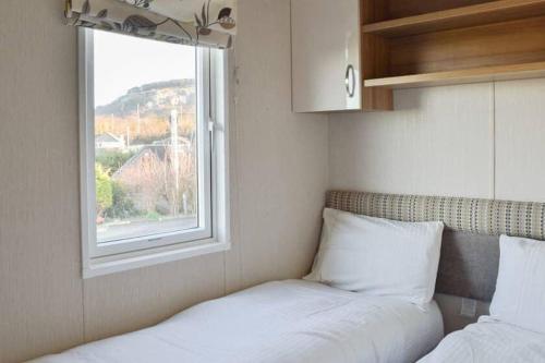 a bed sitting next to a window in a room at Sea View Platinum Caravan in Llanddulas