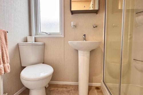 a bathroom with a toilet and a sink and a shower at Sea View Platinum Caravan in Llanddulas