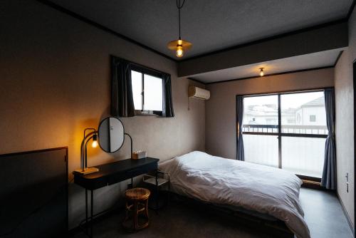 a bedroom with a bed and a desk and a window at 松本市の一棟貸しのプライベート邸宅 in Matsumoto