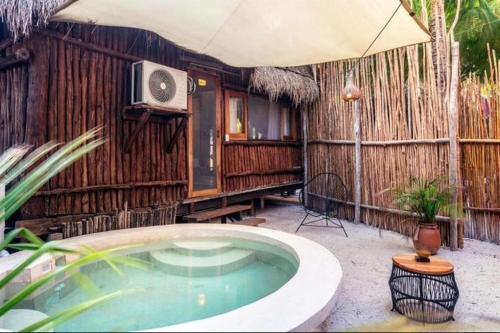 ein Whirlpool mit Fernseher und Sonnenschirm in der Unterkunft Eco Cabañas Laak in Holbox