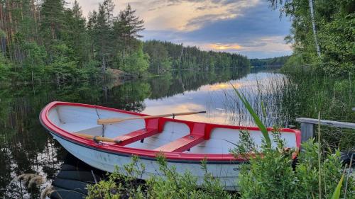 a red and white boat sitting on a lake at Björklunda, lakes, canoe, sauna in Näfstorp