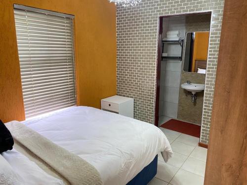 a bedroom with a bed and a bathroom with a sink at 26 Rubens apartments in Secunda