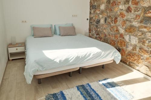a bed in a room with a brick wall at Casa del Bienestar in Lanjarón