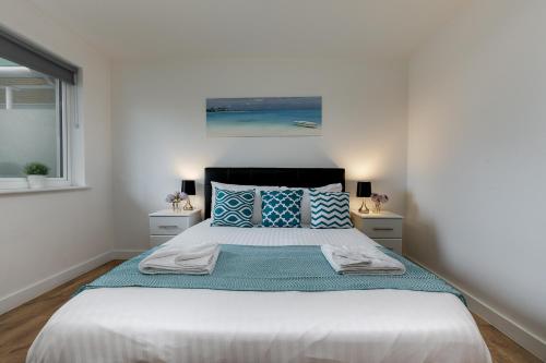 a bedroom with a large bed with blue pillows at Charming 1Bed Flat with Private Balcony, Super Double Bed, Free Allocated Parking, and Easy Access to Tube & Central London in Enfield