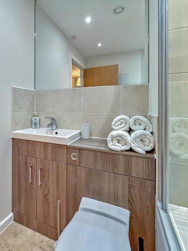 a bathroom with a sink and a toilet and a mirror at PRIME CITY CENTRE MK STAY, Stylish Spacious Apartment, AIR CONDITIONG, Two bathrooms, FREE GATED ALLOCATED PARKING & Lift access in Milton Keynes