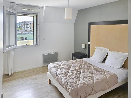 a bedroom with a large bed and a window at Terres de France - Appart Hôtel Rouen Flaubert in Rouen
