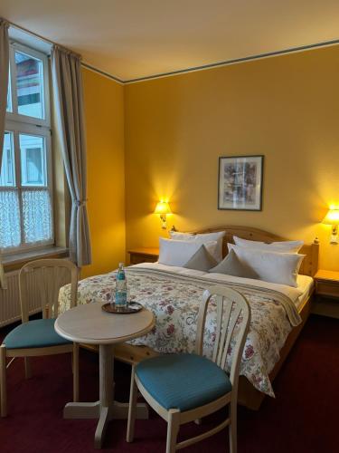 a bedroom with a bed and a table and chairs at Hotel Am Grudenberg in Halberstadt