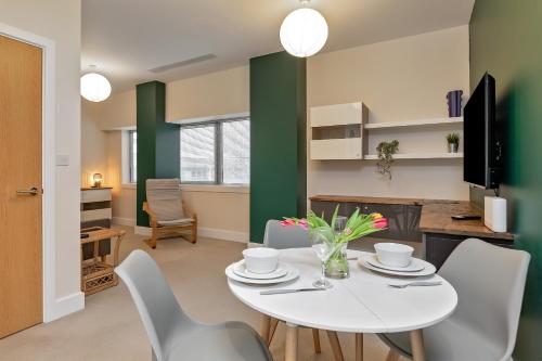 a dining room with a white table and chairs at PRIME CITY CENTRE MK STAY, Stylish Spacious Apartment, AIR CONDITIONG, Two bathrooms, FREE GATED ALLOCATED PARKING & Lift access in Milton Keynes