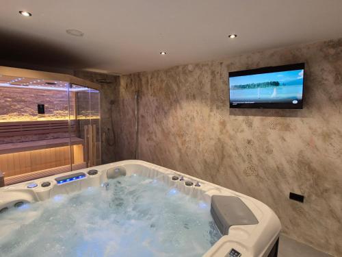 a large bath tub with a tv on a wall at Holiday House Belajec in Popovača