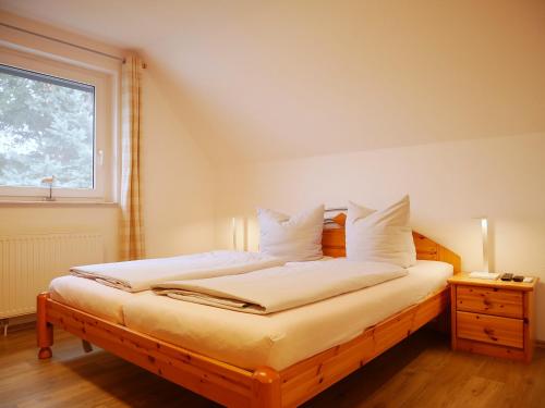a bedroom with a bed with white sheets and a window at Robby2 in Kaltenhof