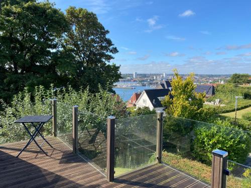a deck with a table and a view of the water at An apartment overlooking the harbor Kolding fjord in Kolding