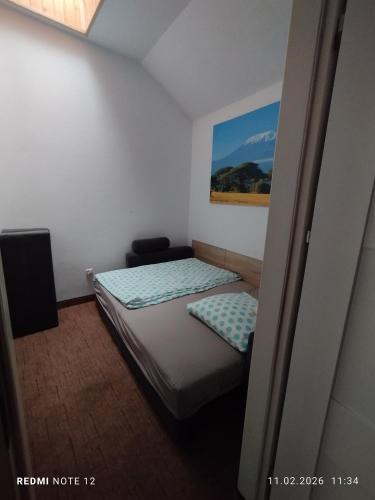 a small bedroom with a bed and a painting on the wall at APARTAMENT W CENTRUM OLESNA in Olesno