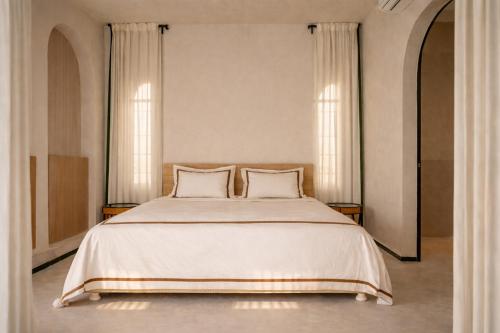 a bedroom with a large white bed with two pillows at Villa Riad- וילה ריאד מתחם נופש יוקרתי in Migdal