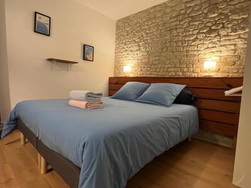 a bedroom with a bed with blue sheets and a stone wall at Gîte La Lézardière avec piscine chauffée privative 30 minutes de la Rochelle in Benon