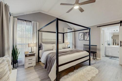 a bedroom with a canopy bed with a ceiling fan at Stunning Rivrefront 3BR with Hot tub, water view! in Seguin