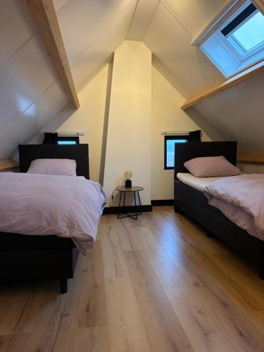 a attic bedroom with two beds and a wooden floor at De Danser 2 in Klaaswaal