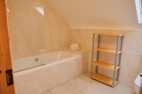 a bathroom with a tub and a book shelf at 5 Bedroom House By Travel Lets Holiday Homes Donegal With Sweeping Lake & Hill Views in Carrigart