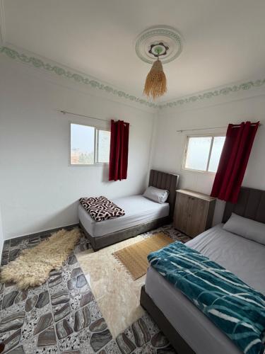 a bedroom with two beds and red curtains at Gaia guest house in Taghazout