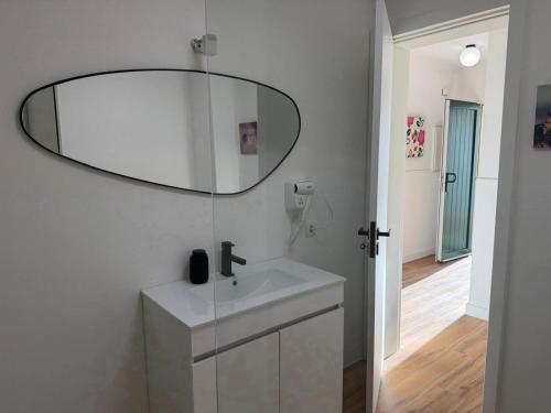 a white bathroom with a sink and a mirror at Azores Pedra Apartaments A in Fajã de Baixo
