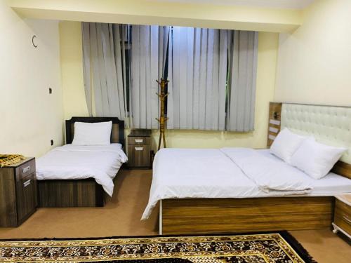 a bedroom with two beds with white sheets and a rug at Star Shirpoor Guest House in Kabul