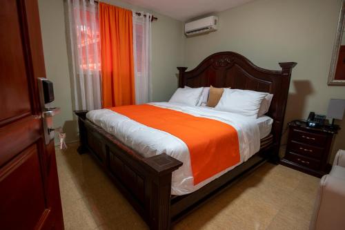a bedroom with a bed with an orange blanket at Vivy Hill's Hotel in Port-au-Prince