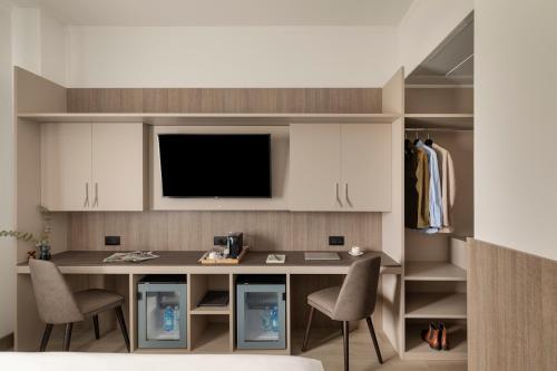 a kitchen with a desk with two chairs and a tv at Living Hotel Milano in Cornaredo