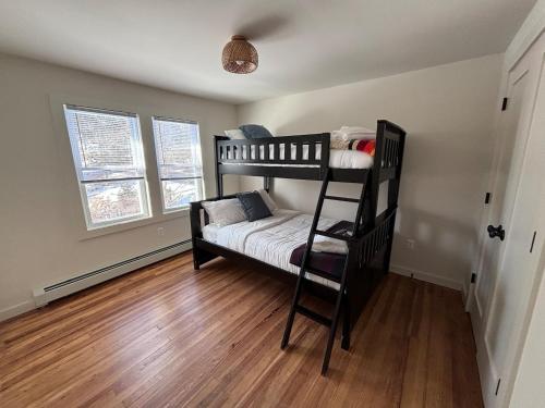 a bedroom with two bunk beds and a wooden floor at Kenoza House with Private Lake and Kayaks in Callicoon