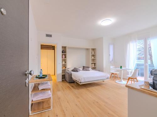 a white bedroom with a bed and a table at GINO SUITES - Monolocali Luxury - Appartamenti vicini a Rho Fiera e Milano in Bollate