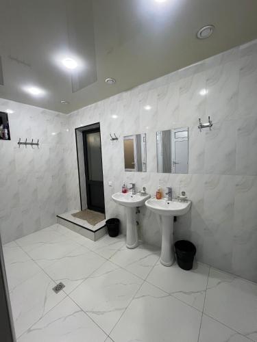 a white bathroom with two sinks and a shower at Hostel Mevazor in Katartal