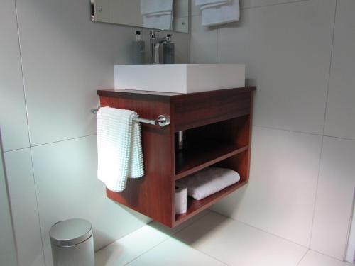 a bathroom with a vanity with a sink and towels at House Sandrock Muckleneuk Selfcatering apartment in Pretoria