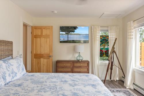 a bedroom with a bed and a dresser and two windows at Lakeshore Vermont in Colchester
