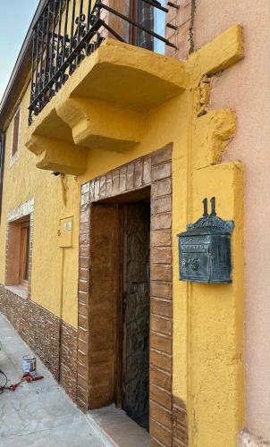 a yellow building with a door and a balcony at Casa rural ‘’La Nuestra’’ in Bercimuel