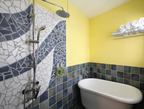 a bathroom with a tub and a shower with blue tiles at Sky Blue Ocean B&B in Eluan