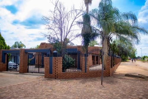 a brick building with a fence and a palm tree at Travel Shift Accommodation in Northam