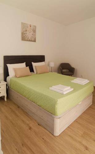 a bedroom with a large bed with green sheets at Casa Isa - Funchal in Funchal