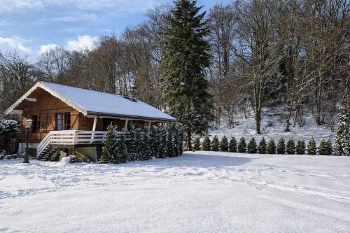 a wooden cabin in the snow with a fence at Auvers Wood lodge in Auvers-sur-Oise