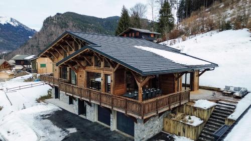 a log cabin with a black roof in the snow at Chalet Imperial by Altitudia in Morzine