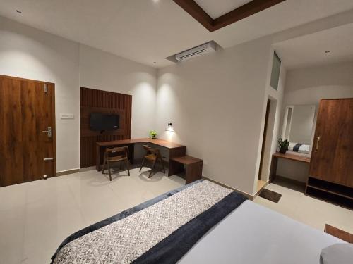 a bedroom with a bed and a desk and a television at KARIPPALS INN in Kottayam