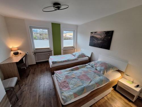 a room with two beds and a desk and two windows at FeWo Waldblick in Waxweiler