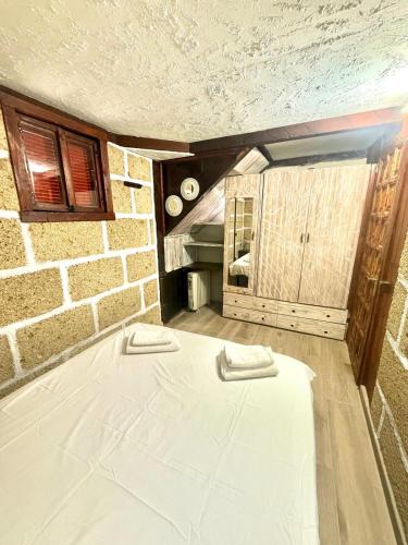 a large white bed in a room with a brick wall at Casa Giuliana in Charco del Pino